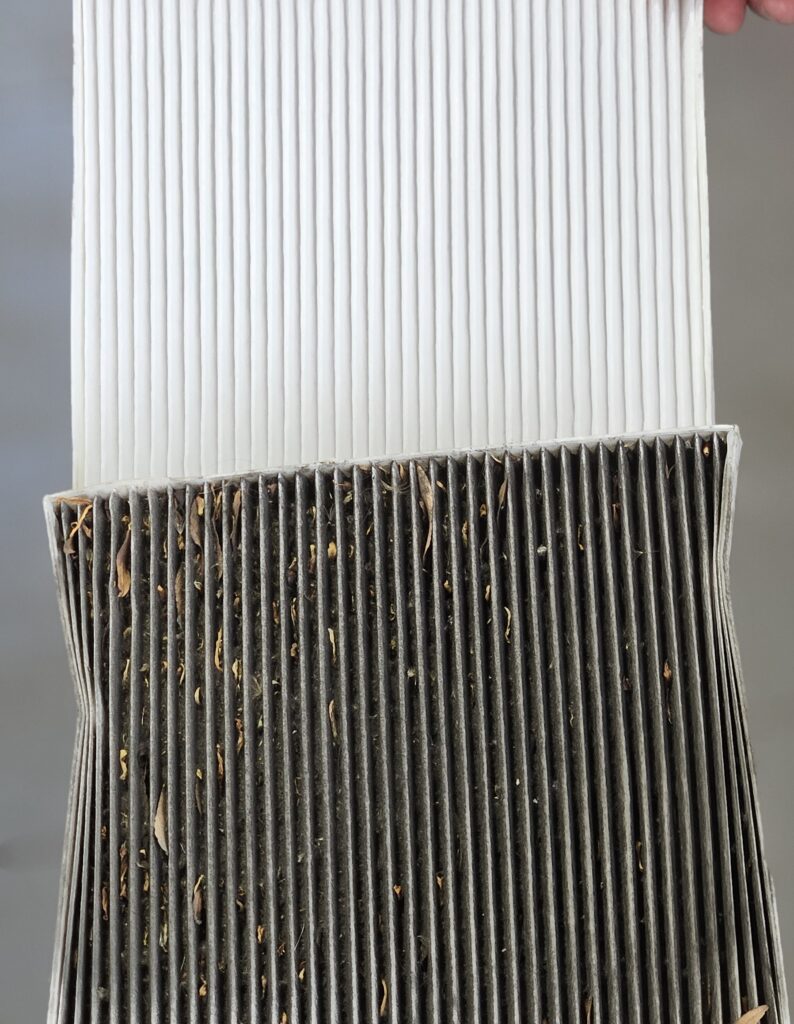 Comparing a dirty cabin air filter to a new one.