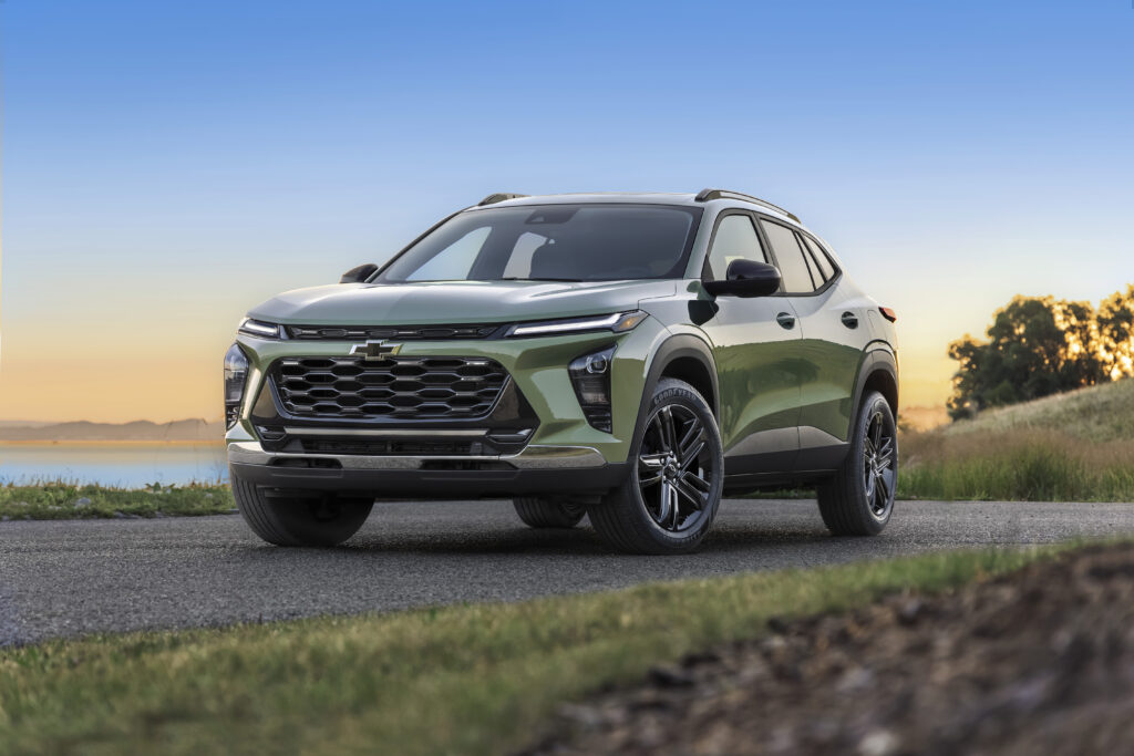 Front 7/8 view of Chevrolet Trax ACTIV in Cacti Green parked on a road in front of a lake. Pre-production model shown. Actual production model may vary. Available in spring 2023. Cacti Green exterior color late availability.