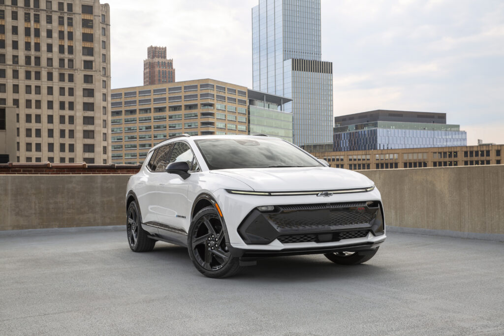 Front 3/4 view of a 2024 Chevrolet Equinox EV RS in Summit White parked on the roof of a parking garage.