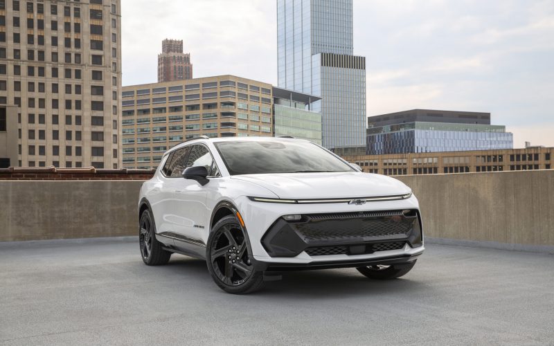 Front 3/4 view of a 2024 Chevrolet Equinox EV RS in Summit White parked on the roof of a parking garage.