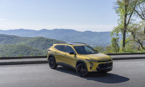 Front 3/4 view of 2024 Chevrolet Trax ACTIV in Nitro Yellow Metallic parked on a road with mountains in the horizon.