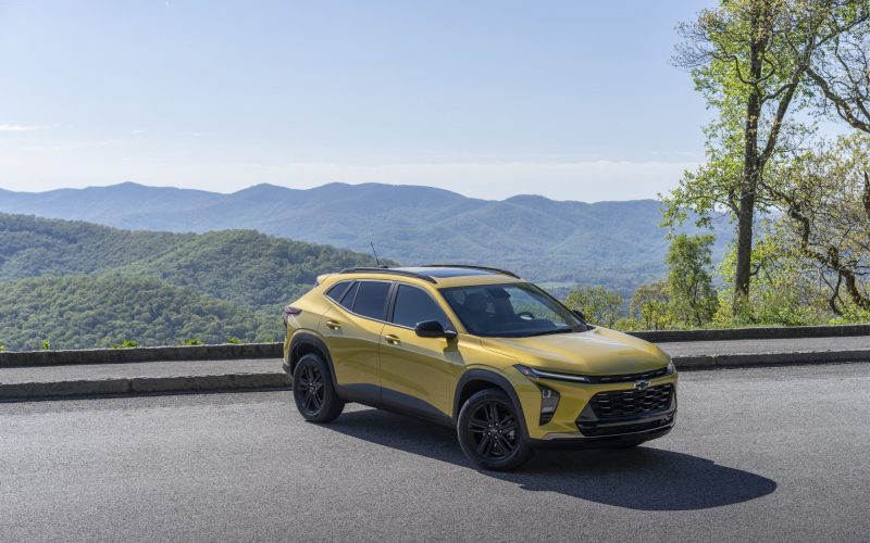 Front 3/4 view of 2024 Chevrolet Trax ACTIV in Nitro Yellow Metallic parked on a road with mountains in the horizon.