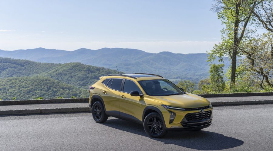 Front 3/4 view of 2024 Chevrolet Trax ACTIV in Nitro Yellow Metallic parked on a road with mountains in the horizon.